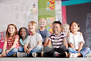 Group Of Elementary School Pupils Sitting On Floor In Classroom