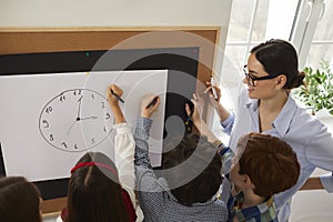 Group of elementary school students drawing a clock and learning to tell the time