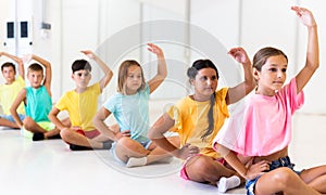 Group of emotional children doing yoga in dance studio