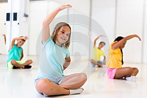 Group of emotional children doing yoga in dance studio