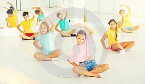 Group of emotional children doing yoga in dance studio