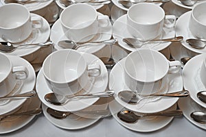 A group of empty white cups and saucers with a teaspoon.