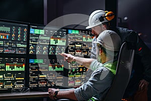 Group of engenners following production line using computer screens with Industry 4.0. Couple of factory operators controll