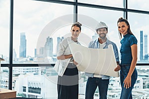 Group of engineer looking at camera while holding project plan. Tracery.