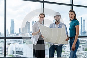 Group of engineer looking at camera while holding project plan. Tracery.