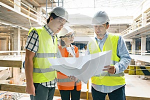 Group of engineers, builders, architects on the building site, looking in blueprint. Construction, development, teamwork and