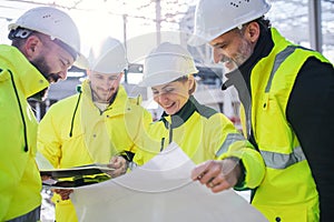 A group of engineers standing on construction site, working.