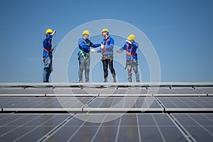 Group of engineers standing on solar panels with blue sky