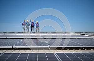 Group of engineers standing on solar panels with blue sky