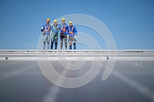 Group of engineers standing on solar panels with blue sky