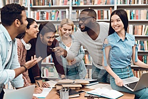 Group of ethnic multicultural students discussing studying in library. photo