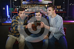 Group of excited friends in beer pub watching sports match