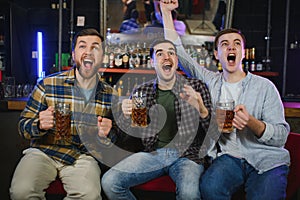 Group of excited friends in beer pub watching sports match