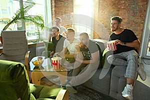 Group of excited friends playing video games at home