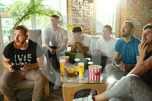 Group of excited friends playing video games at home