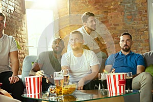 Group of excited friends playing video games at home