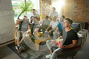 Group of excited friends playing video games at home