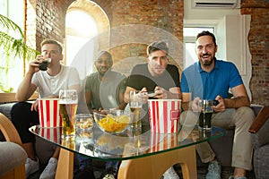 Group of excited friends playing video games at home