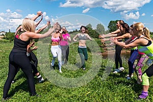 Group of excited women crossing the finshline a marathon running on grassy land in park.