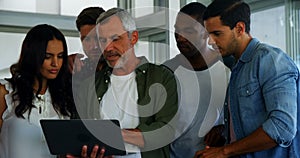 Group of executives discussing over laptop