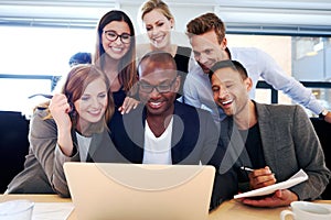 Group of executives gathered around laptop