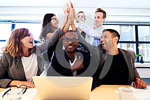 Group of executives high fiving over colleague's head photo