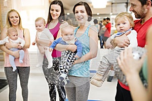 Group exercise class, mother working out with baby in gym. Moms staying active while boding with babies.