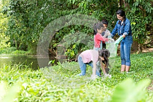 Group family asian children collecting garbage and plastic on the river to dumped into the trash for volunteer charity save enviro