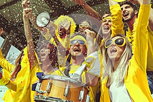 Group of fans dressed in yellow color watching a sports event