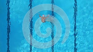 A group of female athlete performs synchronized swimming routines in an outdoor pool, as seen from the air