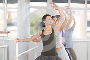 Group of female beginners performing plie at barre