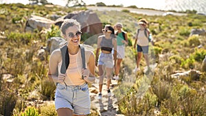 Group Of Female Friends With Backpacks On Vacation On Hike Through Countryside Next To Sea