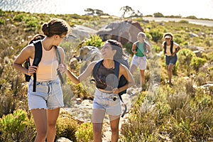 Group Of Female Friends With Backpacks On Vacation On Hike Through Countryside Next To Sea