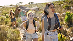 Group Of Female Friends With Backpacks On Vacation On Hike Through Countryside Next To Sea