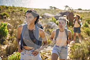 Group Of Female Friends With Backpacks On Vacation On Hike Through Countryside Next To Sea