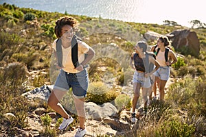 Group Of Female Friends With Backpacks On Vacation On Hike Through Countryside Next To Sea