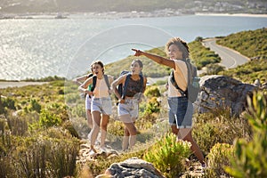 Group Of Female Friends With Backpacks On Vacation On Hike Through Countryside Next To Sea