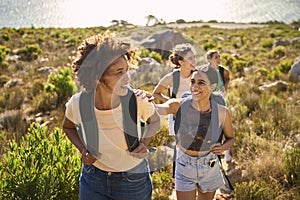 Group Of Female Friends With Backpacks On Vacation On Hike Through Countryside Next To Sea