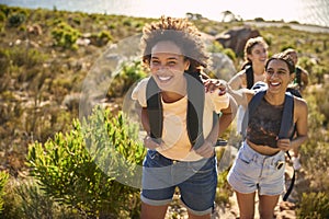 Group Of Female Friends With Backpacks On Vacation On Hike Through Countryside Next To Sea