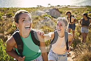 Group Of Female Friends With Backpacks On Vacation On Hike Through Countryside Next To Sea