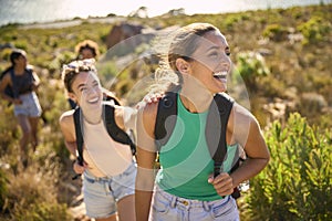 Group Of Female Friends With Backpacks On Vacation On Hike Through Countryside Next To Sea