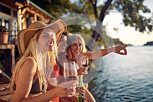 A group of female friends in bikini sitting in the bar on the river and enjoying the view and a drink. Summer, river, vacation