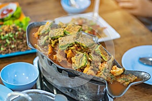 Group of female friends enjoy eating with acacia pennata omelette sour soup in fish shape hot pot in the restaurant.