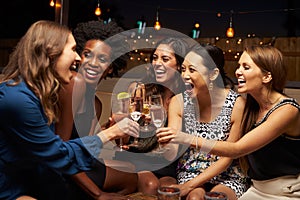 Group Of Female Friends Enjoying Night Out At Rooftop Bar