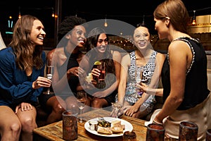 Group Of Female Friends Enjoying Night Out At Rooftop Bar