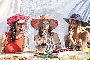 Group of female friends having fun while eating cherries on the roofs