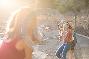 Group of female friends playing tug of war with rope at garden. Women enjoying summer holidays together. Excited female friends