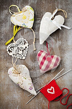 Group of festive hearts from various materials, cloth, wool, wooden, on an old brown concrete or stone background. Selective focus