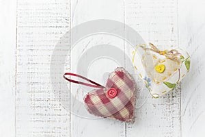 Group of festive hearts from various materials, cloth, wool, wooden, on white wooden background. Selective focus. Vintage