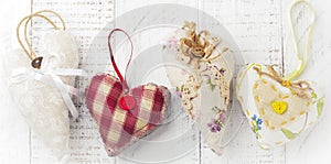 Group of festive hearts from various materials, cloth, wool, wooden, on white wooden background. Selective focus. Vintage
